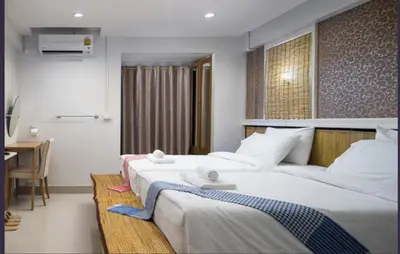 two beds in a hotel room with a desk and a room at bang khun thian14 in Sathani Wat Sing