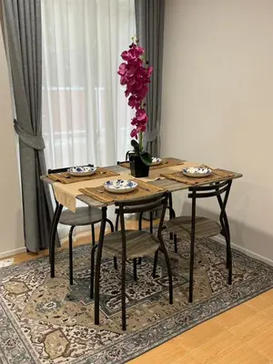 a wooden table with chairs and a vase with pink flowers at EM HOME Sukhumvit Bangkok - near Terminal 21, EM District Malls, BTS and MRT Lines in Bangkok