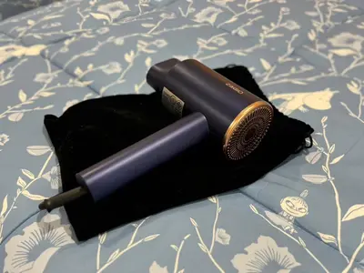 a hair dryer sitting on top of a bed at EM HOME Sukhumvit Bangkok - near Terminal 21, EM District Malls, BTS and MRT Lines in Bangkok