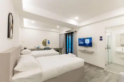 a white bedroom with three beds and a shower at P9 Ratchada Hotel in Bangkok