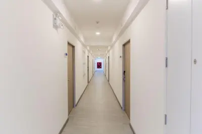 an empty corridor of an empty hospital hallway with white walls and a long corridor at P9 Ratchada Hotel in Bangkok