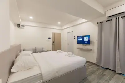 a white bedroom with a bed and a tv at P9 Ratchada Hotel in Bangkok