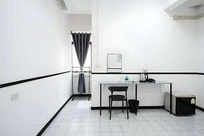 a white room with a table and a chair at XX GO INN MRT Hua Lamphong China Town in Bangkok