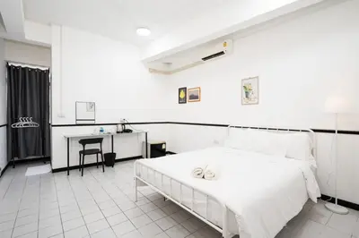 a white bedroom with a bed and a desk at XX GO INN MRT Hua Lamphong China Town in Bangkok