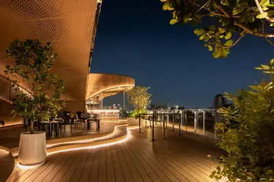 a rooftop deck with tables and chairs at night at Somerset Sukhumvit 71 Bangkok in Bangkok
