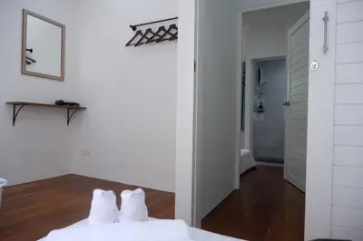 a bedroom with white walls and a bed with white pillows at Oskar's House in Bangkok