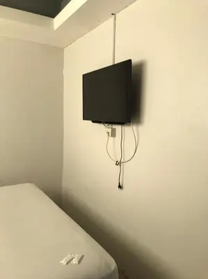 a room with a bed and a flat screen tv on the wall at Rod Fai Fah Apartment in Bangkok
