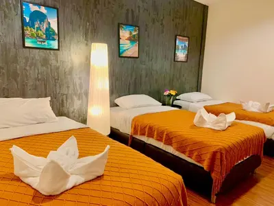 a hotel room with three beds with orange sheets at The City Yaowarat in Samphanthawong