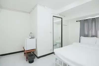 a white bedroom with a bed and a mirror at GO INN Bangkok Rama3 โกอินน์ พระราม3 in Bangkok