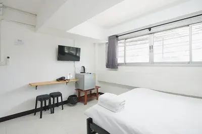 a room with two beds and a desk and a window at GO INN Bangkok Rama3 โกอินน์ พระราม3 in Bangkok