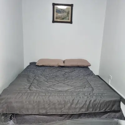 a bed in a white room with a gray blanket at Popular Muang Thong Thani Condo, Building T9, Floor 8, Room 13 in Pak Kret