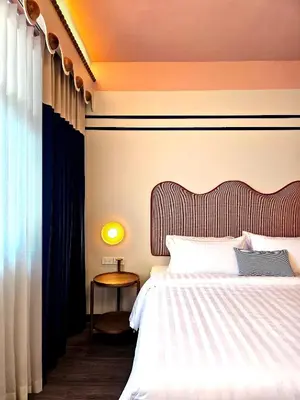 a bedroom with a bed and a table and a window at Blu Dock Restel Bangkok in Bangkok