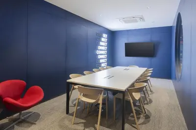 a conference room with blue walls and a table and chairs at Riva Vibe Hotel Bangkok by PCL in Bangkok