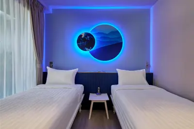 two beds in a room with a blue wall at Riva Vibe Hotel Bangkok by PCL in Bangkok