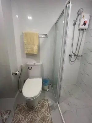 a white bathroom with a toilet and a shower at Great Value Apartment in Bang Khen