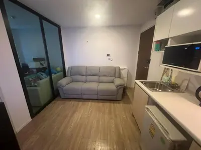 a living room with a couch and a kitchen at Great Value Apartment in Bang Khen