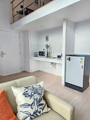 a living room with a couch and a kitchen at Midtown Duplex Ratchayothin in Bangkok