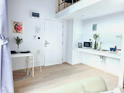 a white living room with a table and a microwave at Midtown Duplex Ratchayothin in Bangkok