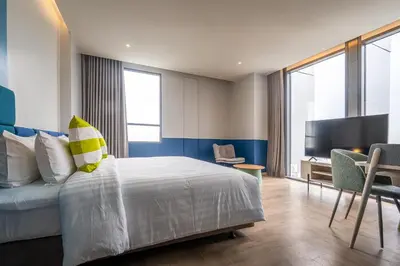 a bedroom with a bed and a desk and a tv at The Quarter Ramkhamhaeng by UHG in Bangkok
