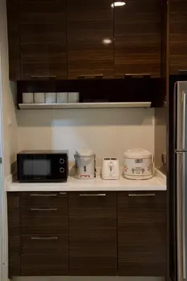 a kitchen with wooden cabinets and a microwave and appliances at Entire Townhome 3BR3B, Pool, Sukhumvit-EmSphere in Bangkok