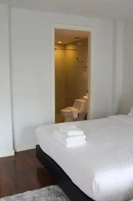 a bedroom with a white bed and a bathroom at Entire Townhome 3BR3B, Pool, Sukhumvit-EmSphere in Bangkok