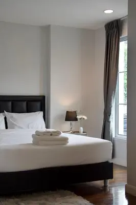a bedroom with a bed with white sheets and a window at Entire Townhome 3BR3B, Pool, Sukhumvit-EmSphere in Bangkok