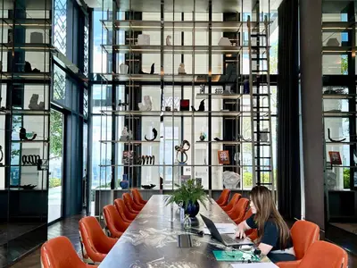 a woman sitting at a long table with a laptop at The Address Siam Luxury Two Bedrooms in Bangkok