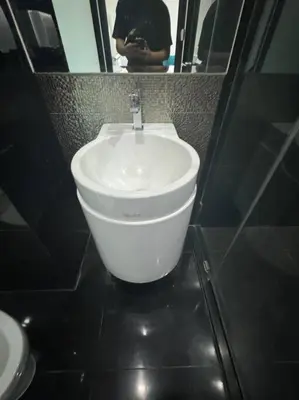 a white sink in a bathroom with a person in the mirror at Thong Lor, Sukhumvit 36 in Bangkok