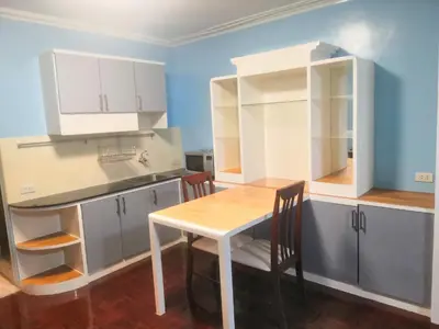 a kitchen with white cabinets and a table and chairs at Silom room 40 sqm with 2 Queen beds for 4 persons in Bangkok