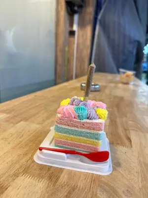 a rainbow cake on a plate on a table at The LODGE BKK Hostel in Bangkok