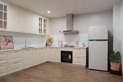 a kitchen with white cabinets and a refrigerator at Naiya Bangkok in Bangkok