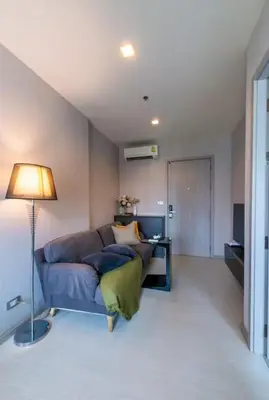 a living room with a blue couch and a lamp at Cozy Apartment With Train Access in Bangkok
