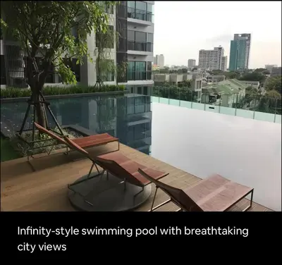 an infinity style swimming pool with a table and chairs at Cozy Apartment With Train Access in Bangkok