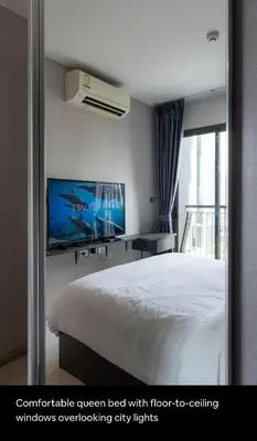 a bedroom with a bed with a tv and a window at Cozy Apartment With Train Access in Bangkok