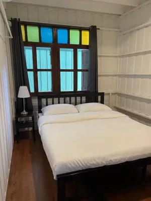 a bedroom with a bed with a window and white sheets at Green Cabin Hostel in Bangkok
