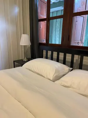 a bed with two white pillows and a window at Green Cabin Hostel in Bangkok