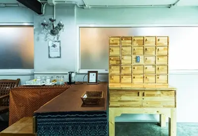 a wooden desk in a room with a table at XX GO INN Khaosan - The Grand Palace ตรอกข้าวสาร in Bangkok