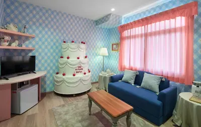 a living room with a blue couch and a cake at Kitsch Hotel in Bangkok
