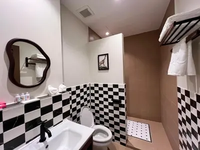 a bathroom with a black and white checkered wall at Kitsch Hotel in Bangkok