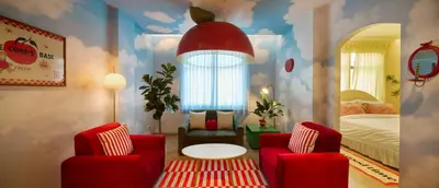 a room with a bed and two red chairs at Kitsch Hotel in Bangkok