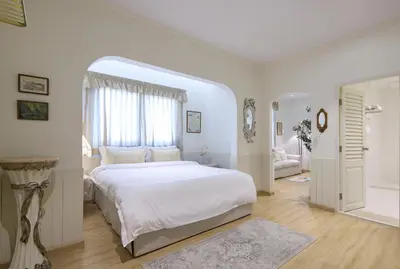 a white bedroom with a large bed and a bathroom at Kitsch Hotel in Bangkok