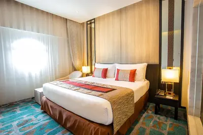 a hotel room with a large bed and a window at Grace Hotel in Bangkok