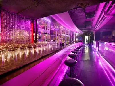 a bar with purple lights and bar stools at Grace Hotel in Bangkok