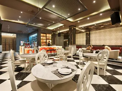 a restaurant with white tables and chairs and people in the background at Grace Hotel in Bangkok