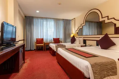 a hotel room with two beds and a flat screen tv at Grace Hotel in Bangkok