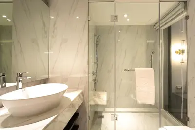 a bathroom with a sink and a glass shower at Grace Hotel in Bangkok