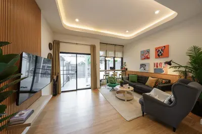 a living room with a couch and a tv at Cozy Spacious 4BR Villa, 12pax, 200m BTS PhraKhanong, 10min ThongLo, Fast 500mbps Wifi in Bangkok
