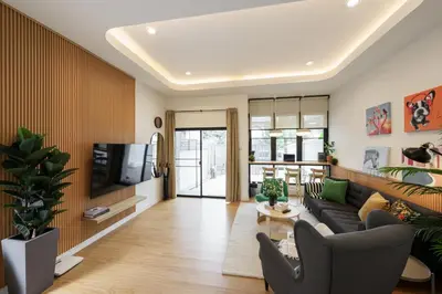 a living room with a couch and a tv at Cozy Spacious 4BR Villa, 12pax, 200m BTS PhraKhanong, 10min ThongLo, Fast 500mbps Wifi in Bangkok