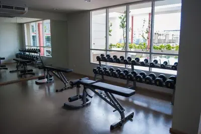 a gym with rows of exercise equipment and windows at Cozy Living in Bangkok 60m to MRT near chatuchank in Bang Su