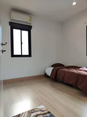 a bedroom with a bed and a window at Baan Salaya in Salaya